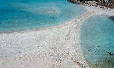 Turkuaz suyu ve ıssız adasıyla tropikal plajın insansız hava görüntüsü. Nissi plajı, Ayia Napa, Kıbrıs
