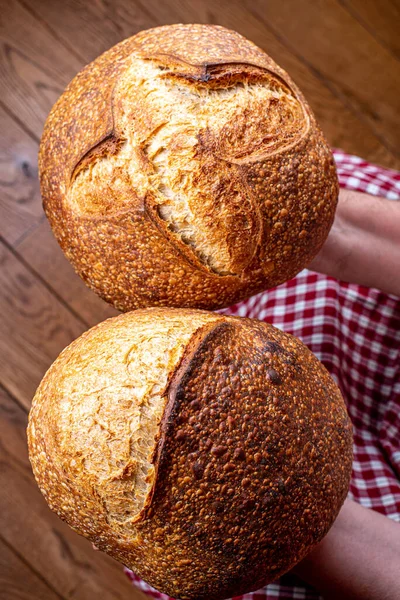 Sourdough bread with crispy crust in baker hands. Healthy food photography