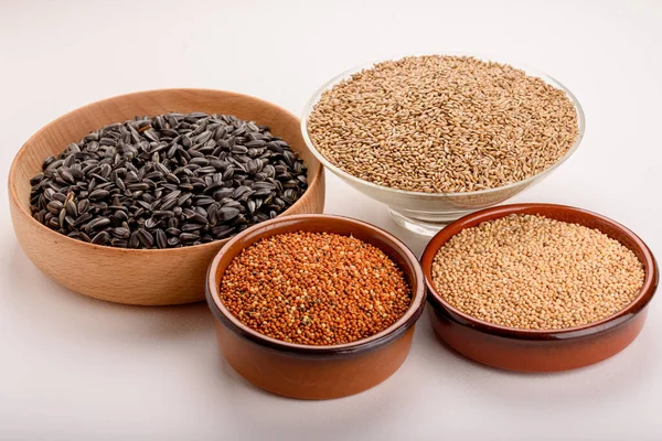 Dried grains bird food. Red millet grain, yellow millet grain, black sunflower seeds and canary grass seeds in pots.