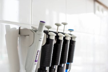 Duvar tutacağında birkaç pipet var. Otomatik pipetler, laboratuvar ekipmanları. Mikro pipetler, kimyasal ekipmanlar.