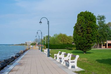 Balaton Gölü kıyısında yeşil ağaçları, çiçekleri, bankları ve lambaları olan bir meydan..