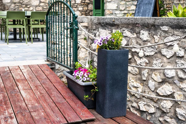 stock image a flower-decorated entrance with green metallic gate to a bar or restaurant with a Mediterranean atmosphere.