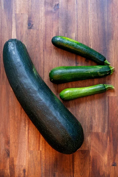 Big and small zucchinis. Fresh zucchini on wooden background. Organic corgettes or zucchini on a wooden table