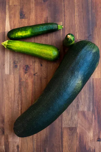 Big and small zucchinis. Fresh zucchini on wooden background. Organic corgettes or zucchini on a wooden table