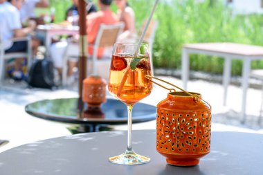 bir bar masasında portakal suyu, kokteyl ve seramik mum tutacağı..