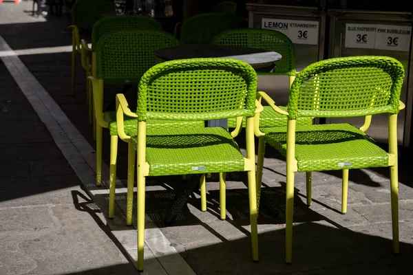 Green chairs and table in restaurant on the street.