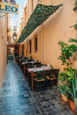 Rethymno 'nun dar sokaklarında masa ve sandalyeler.