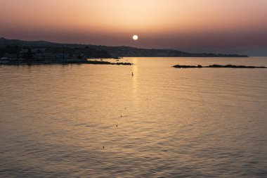 Günbatımında denizde sörf yapan bir adam. Bir sörfçü, sahilin üzerine sarı bir parıltı saçarak, güneş batarken sörf tahtasında huzurlu bir anın tadını çıkarır..