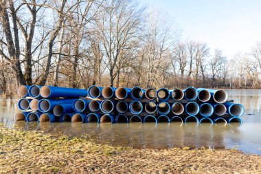 İnşaat için bekleyen borular yığıldı ve nehir kıyısındaki ağaçlar sular altında kaldı..