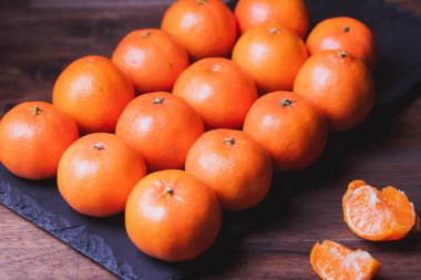 Mandalina meyvesi. Siyah taş tahtada sıra sıra dizilmiş mandalina fotoğrafları.