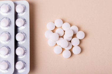 Bej arka plandaki su toplamasına sarılı beyaz hapların ve hapların yakın plan görüntüsü..