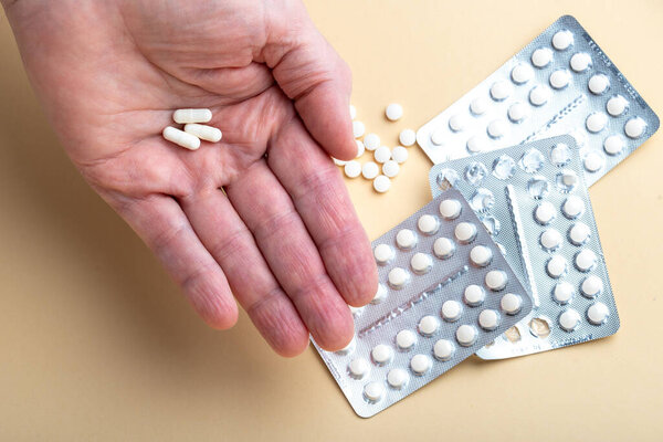 Male hand holding three capsules with medicine, vitamins or sports supplement in hand on yellow background. Close up of Vitamin D pills in blister packs on yellow background.