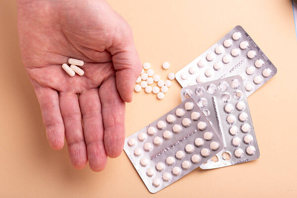 Male hand holding three capsules with medicine, vitamins or sports supplement in hand on yellow background. Close up of Vitamin D pills in blister packs on yellow background.