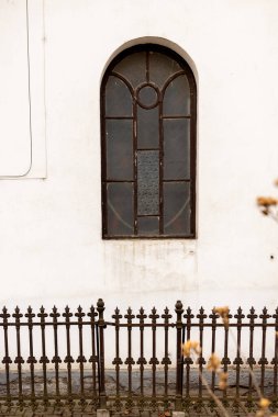Eski kilisenin beyaz duvarında klasik kahverengi ahşap pencere, metalik çit.