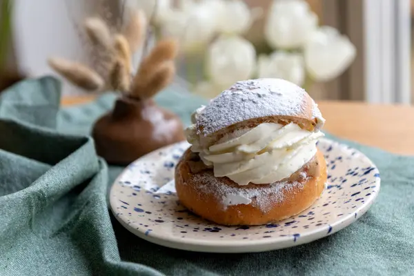 Typical Swedish semla with sweet cream on te blue textile.