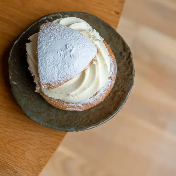 Typical Swedish semla with sweet cream on the wooden table.