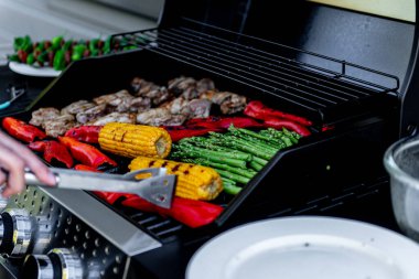 Lezzetli ızgara tavuk eti, sebzeli kuşkonmaz, paprika ve mısır koçanı ızgarada duman ve alevle birlikte..