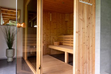 Banklı ahşap sauna. Sauna boş. Ahşap banklar insanlara oturma olanağı sağlıyor. Küçük ev ahşap sauna, spa odası. Sıcak bir saunada rahatla..