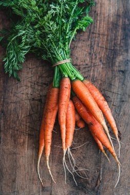 Ahşap zemin üzerinde turuncu havuçlar. Bir demet organik taze havuç ve yeşil havuç..