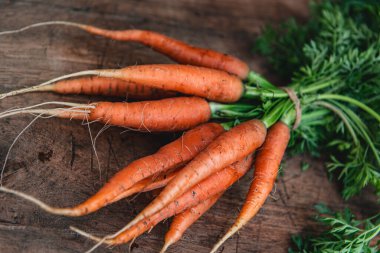 Ahşap zemin üzerinde turuncu havuçlar. Bir demet organik taze havuç ve yeşil havuç..