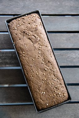 Pişirmeden önce ev yapımı çavdar ekmeği şeklinde mayalanmış ekşi ekmek. Bir somun ekmek ve kişniş tohumları pişirilmeye hazır. Tahta masada ekmek var.