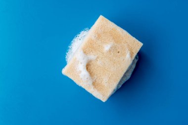 Mavi seramik masada bulaşık yıkamak için köpük süngeri, kopyalama alanı.