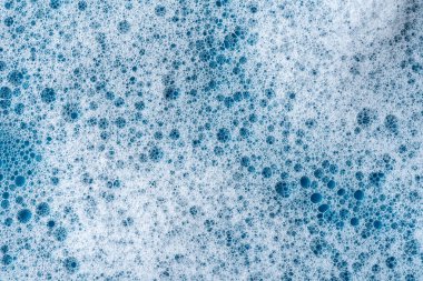 Geçmişi ve düzeni. Kabarcıklı beyaz sabun köpüğü, mavi fayans kaplamalı doku. Döşeme üzerinde deterjan köpüğü. Duş jeli, saç şampuanı köpük lekesi dokusu. Güzellik, temizlik ve çamaşır.