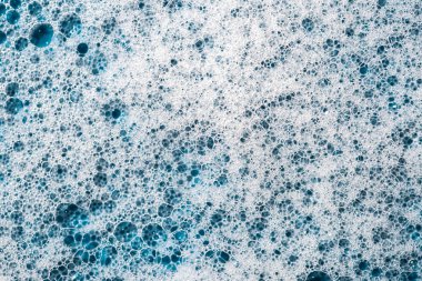 Geçmişi ve düzeni. Kabarcıklı beyaz sabun köpüğü, mavi fayans kaplamalı doku. Döşeme üzerinde deterjan köpüğü. Duş jeli, saç şampuanı köpük lekesi dokusu. Güzellik, temizlik ve çamaşır.