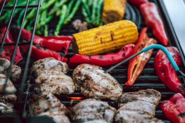 Lezzetli ızgara tavuk eti, sebzeli kuşkonmaz, paprika ve ızgarada ızgara mısır koçanı duman ve alevle birlikte. Güvenli yiyecek sıcaklığı için dijital hazır termometre ile tavuğu kontrol ediyorum..