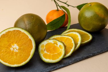 Navel Chocolate Oranges on the black stone board. Chocolate orange, is a type of Navel orange, a mutation that was first discovered in 2006 in Valencia, Spain. clipart