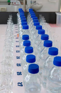 Beyaz masada mavi polipropilen kapaklı laboratuvar şişeleri. Laboratuvar ekipmanları