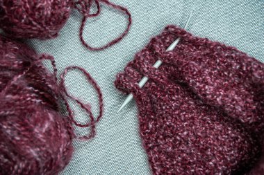 Gri arka planda iplikler, örgü iğneleri ve örnek örnekleri var. Yakın çekim