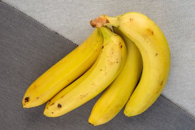 Gri arka planda bir grup olgun sarı muz ve sabahın erken saatlerinde güneş ışığı parlıyor.