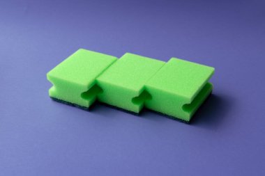 Pembe arka planda bulaşık süngeri. Çevre dostu yemek, pembe arka planda yeşil tonları süngerler. Sürdürülebilir ev veya temizlik temaları için minimalist kompozisyon.