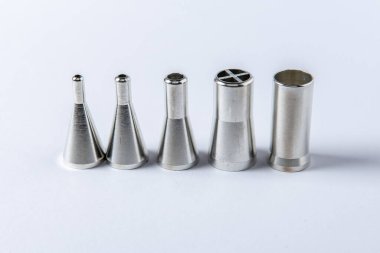 Elektronik imalat için otomatik lehimleme makinelerinde kullanılan, beyaz arka planda, paslanmaz çelik lehim başlıklarını dağıtan yakın plan..