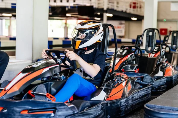 teenage boy in a racing helmet gets ready to race. Indoor kart track