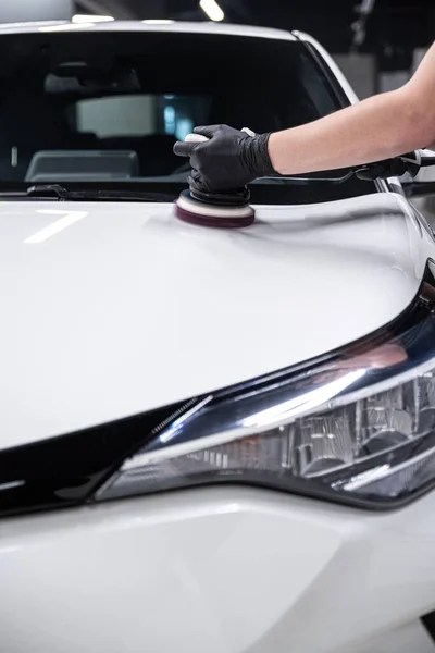 洗车或汽车维修车间的员工用电动抛光机擦亮白色汽车的漆面 — 图库照片