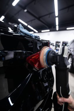 Oto yıkama ya da araba tamircisi siyah bir arabanın boyasını parlatır.