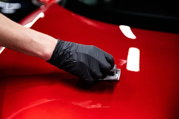 洗车厂或汽车维修车间的员工将陶瓷涂层涂在红色汽车的油漆上 — 图库照片