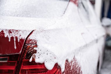 El yıkamada beyaz köpükle kaplanmış kırmızı araba.