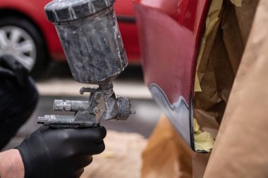 Boyacı kırmızı bir arabanın tamponunda boya hasarı, boya servisi....