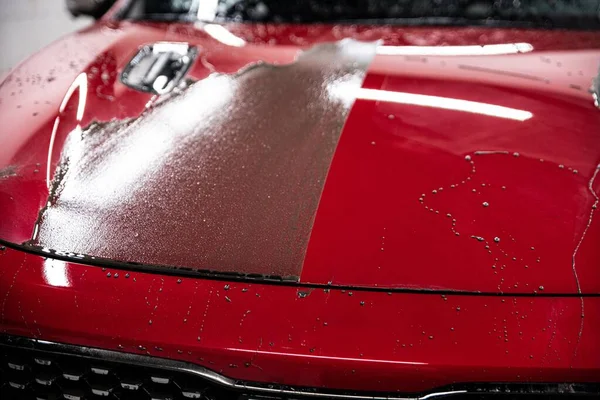 Effect after applying a ceramic coating on a red car. Right side of the mask is coated and the left side is uncoated