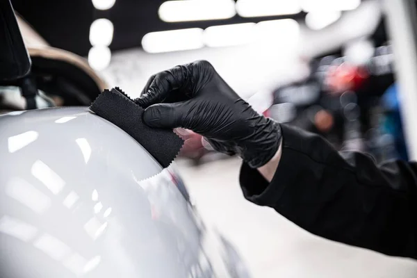 汽车详细工作室或洗车公司的员工使用特殊的喷涂器将陶瓷涂层涂在白色汽车的油漆上 — 图库照片