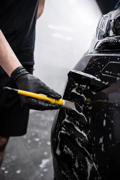 スタジオの従業員を詳述した車の洗浄または車の洗剤を使用して車のバンパーの一部を掃除しています — ストック写真