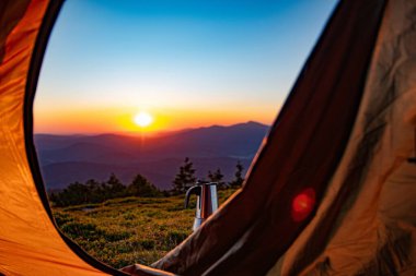 Kahve yapmak için bir cihaz - Polonya dağlarındaki bir dağın tepesindeki bir çadırın önündeki gaz ocağında bir moka tenceresi - Beskidy. Bir dağ kampında gün doğumu.