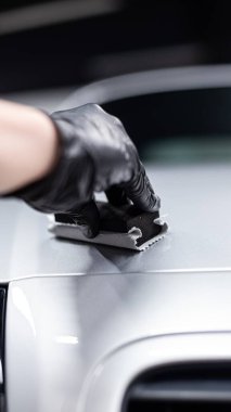 Araba yıkama stüdyosu ya da araba yıkama çalışanı gümüş bir arabanın boyasına seramik ya da grafen kaplama uygular.