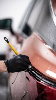 Araba yıkama işçisi ya da araba yıkama stüdyosu arabanın bir kısmını dikkatlice fırçayla temizler.