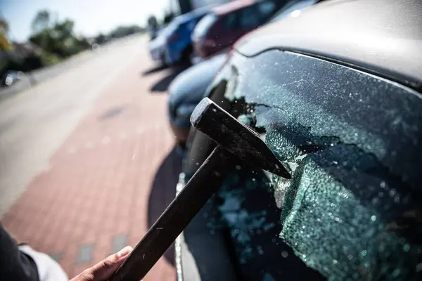 Car thief breaks the car window with a hammer