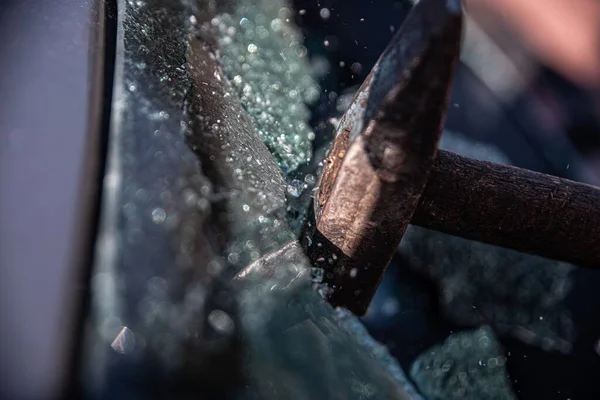 Car thief breaks the car window with a hammer