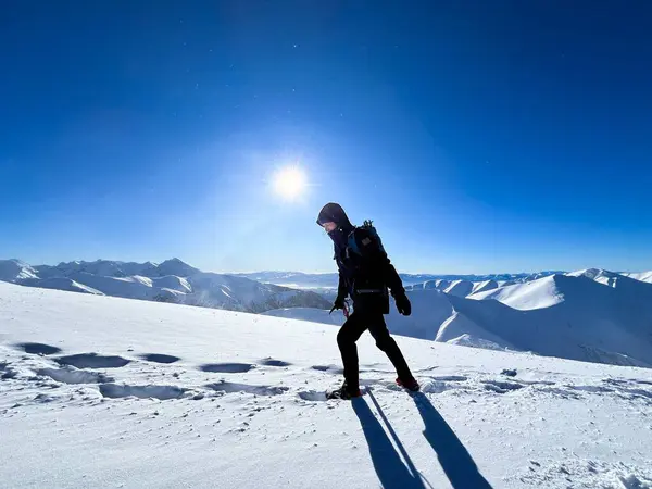 Adventurer conquering the frosty slopes of the Polish Tatras, sun blazing above
